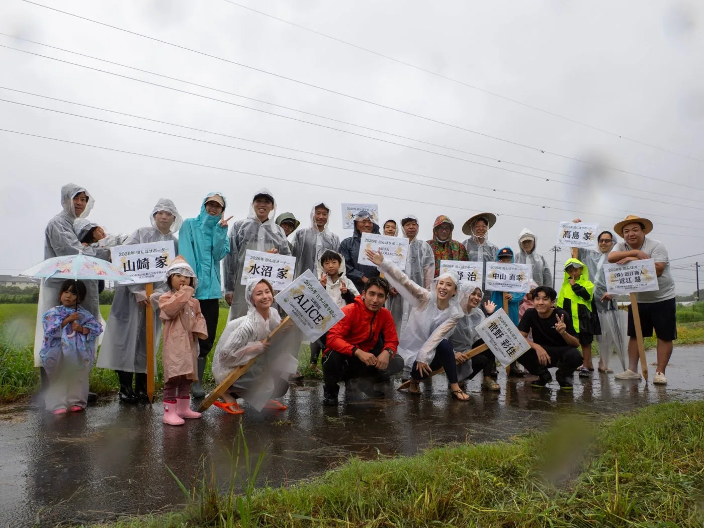 雨の田んぼで集合写真に写る参加者