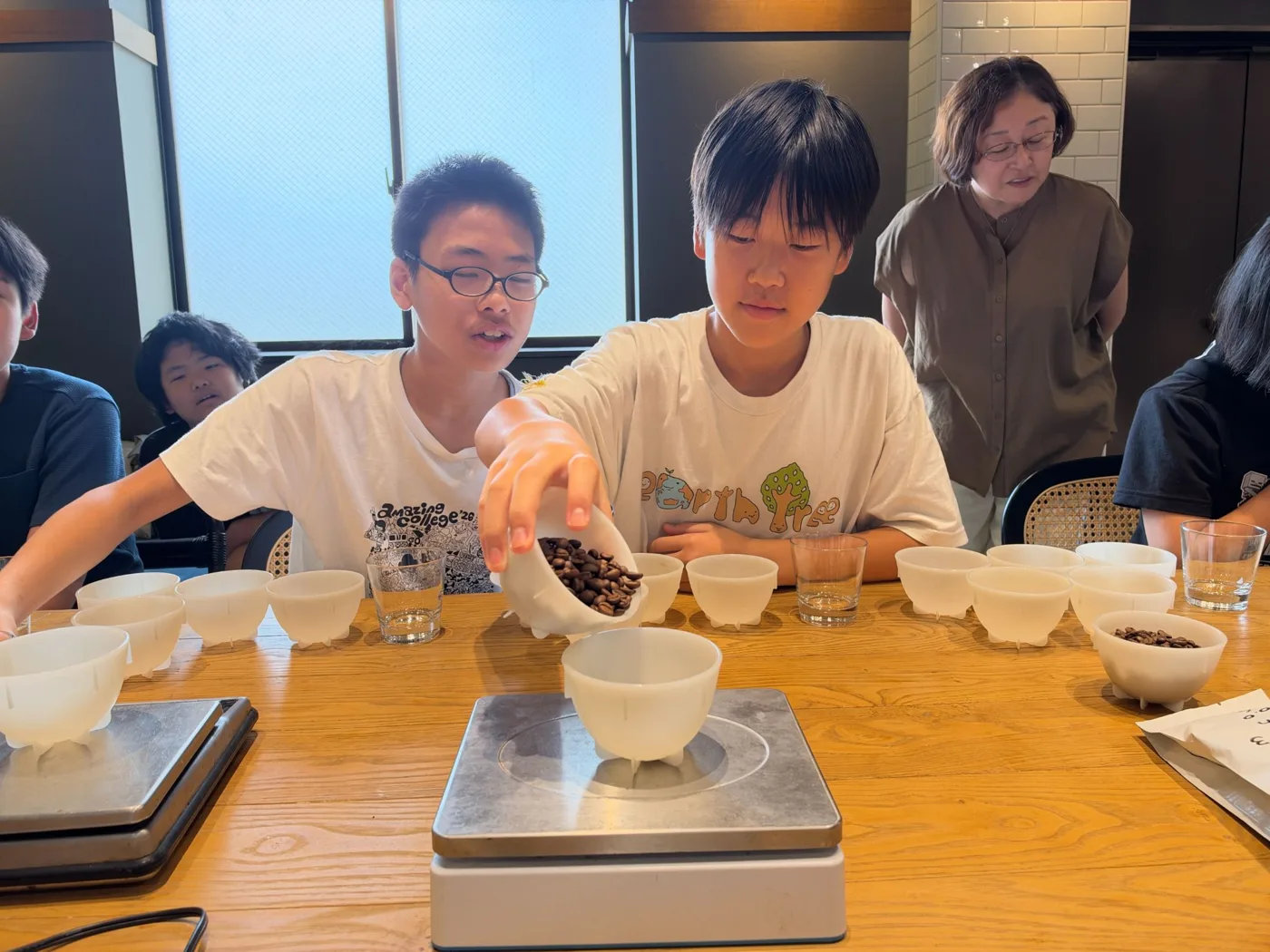 コーヒー豆を計量カップに分ける子どもたち