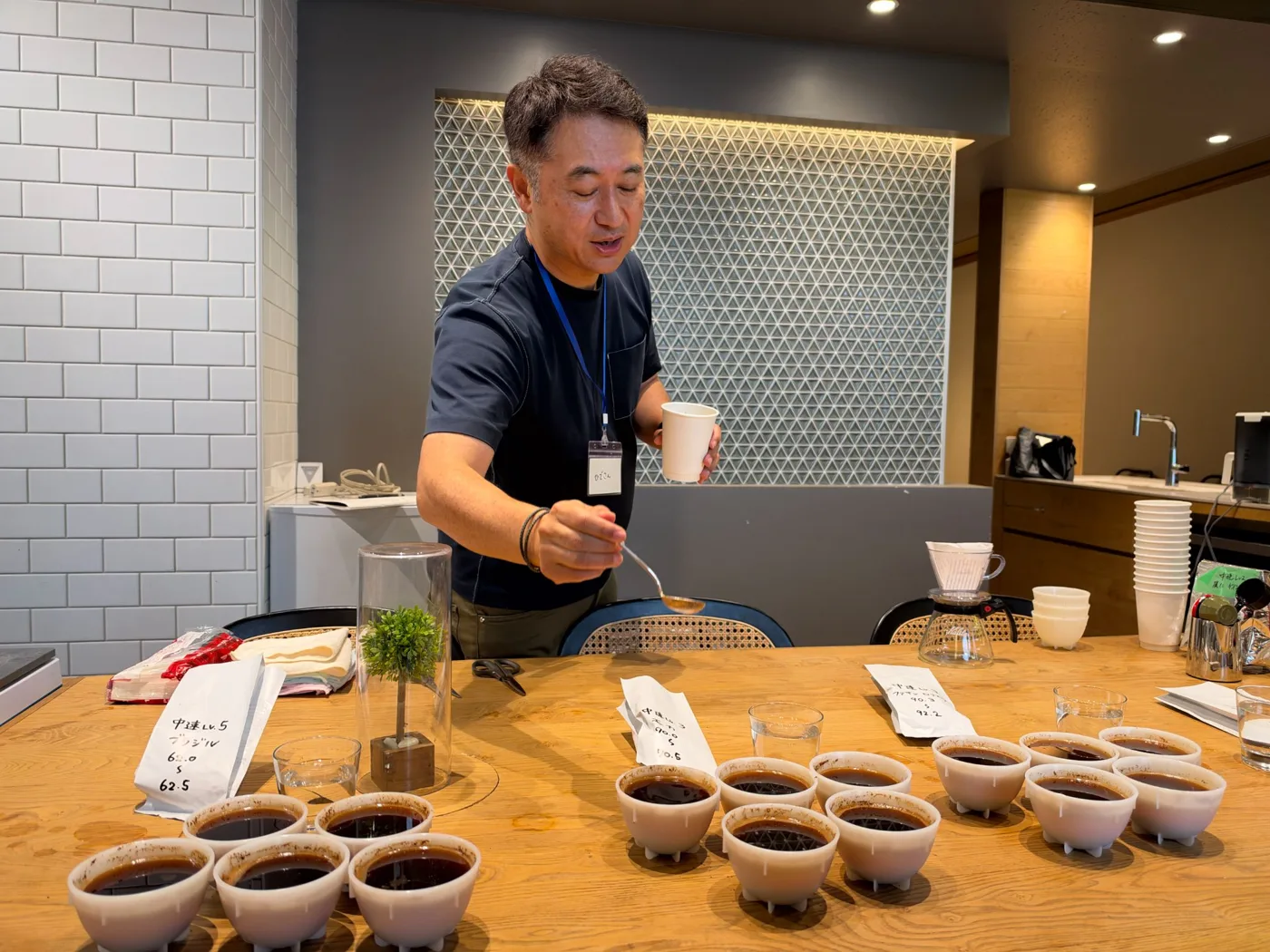 カッピングのカップを前にテイスティングする田中英樹さん
